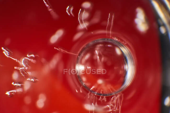 Burbuja transparente de primer plano flotando en la superficie de la bebida roja viva en la taza de vidrio - foto de stock