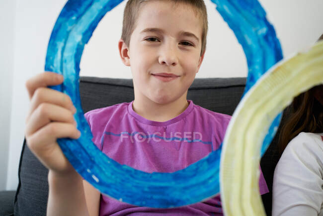 Sorrindo menino segurando com anel azul olhando para a câmera — Fotografia de Stock
