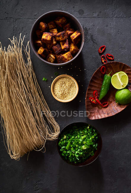 Ингредиенты для приготовления вегетарианского рамена с тофу уложены на темном фоне — стоковое фото