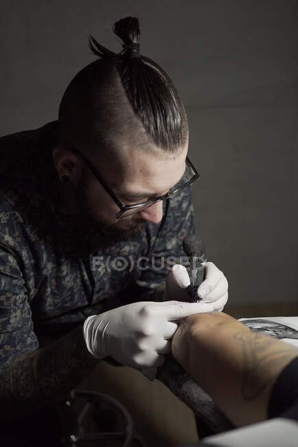 Tatuaggio con macchina e tatuaggio con inchiostro nero nel salone in anonimo cliente ritagliato — Foto stock