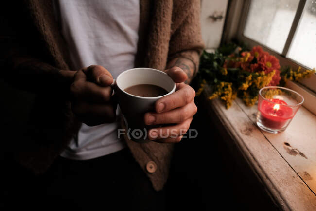 Uomo che tiene il cacao tra le mani vicino alla finestra — Foto stock