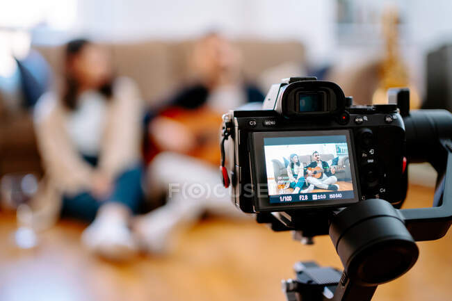 Creative couple of musicians sitting on floor and shooting video on camera while playing acoustic guitar for social media blog — Stock Photo