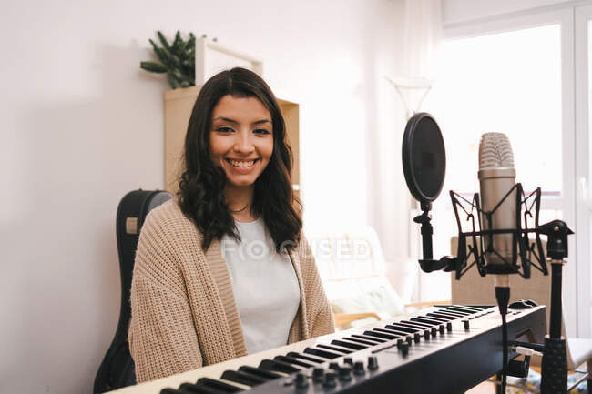 Талановита жінка-музикантка, яка грає на електричному піаніно і створює музику в творчій домашній студії — стокове фото