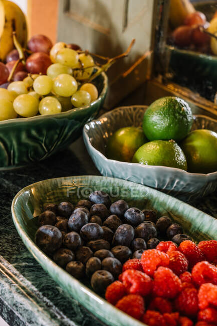 Various ripe fruits and tasty berries in plates served on table for buffet breakfast — Stock Photo