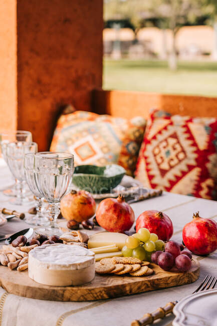 Table servie avec vaisselle et fruits mûrs assortis et délicieux apéritifs sur la terrasse — Photo de stock