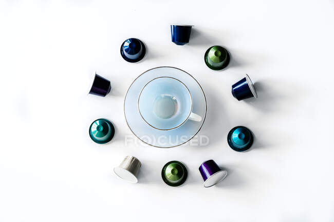 Vue du dessus de la collection de dosettes de café placées près de tasse et soucoupe en céramique vide sur fond blanc — Photo de stock