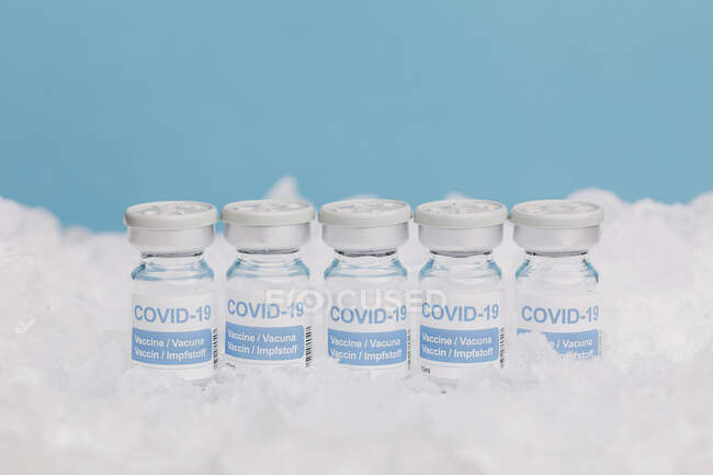 Крупный план стеклянных флаконов с вакциной от COVID 19, помещенной на лед в морозилке — стоковое фото