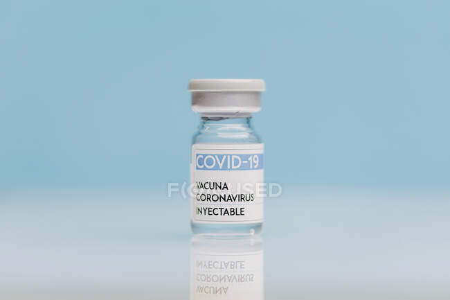 Glasflasche mit Impfstoff von COVID 19 auf Tisch auf blauem Hintergrund — Stockfoto