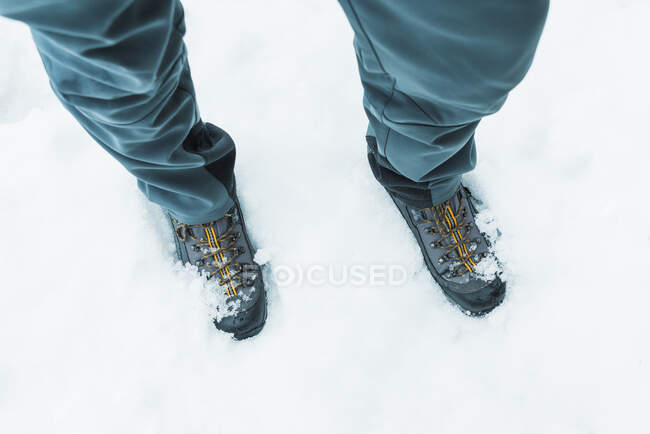 From above of crop unrecognizable hiker in trekking boots standing on snowy ground in winter — Stock Photo