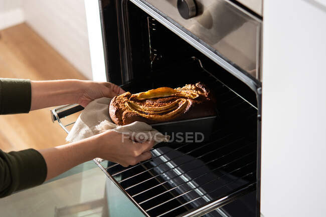 Crop woman taking banana bread out of the oven — Stock Photo