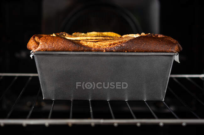 Vista lateral pão de banana saudável em recipiente no forno — Fotografia de Stock