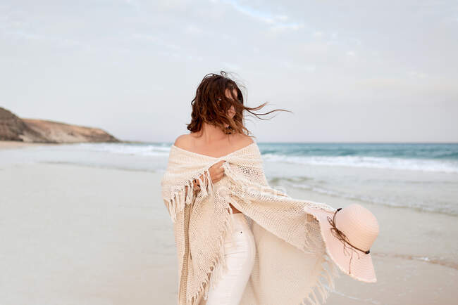 Viajante feminina em óculos de sol e chapéu andando ao longo do litoral e olhando para longe — Fotografia de Stock