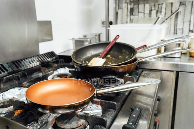 De arriba las sartenes vacías sucias después de preparar el plato a la estufa en la cocina del restaurante - foto de stock