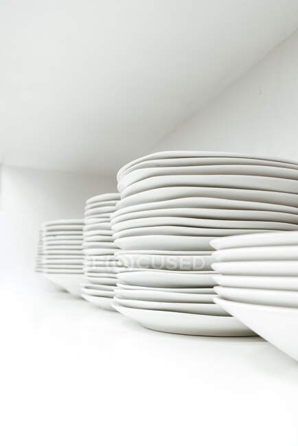 Pilha de placas de cerâmica semelhantes simples colocados uns sobre os outros contra fundo branco no armário de cozinha — Fotografia de Stock