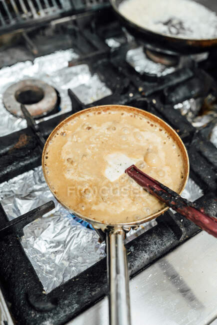 De arriba las sartenes de los platos apetitosos que preparan a la estufa en la cocina del restaurante - foto de stock