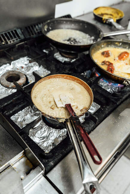Зверху сковороди апетитних страв готують на плиті на кухні ресторану — стокове фото