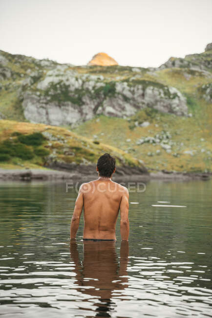 Vue arrière d'un voyageur masculin méconnaissable avec torse nu debout dans les lacs d Ayous en terrain montagneux dans les Pyrénées — Photo de stock