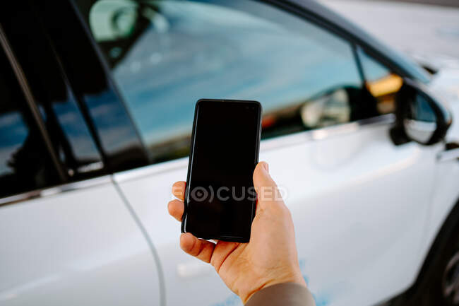 Männlicher Unternehmer entriegelt Tür eines modernen Automobils mit Smartphone und nutzt Fernbedienungs-App — Stockfoto