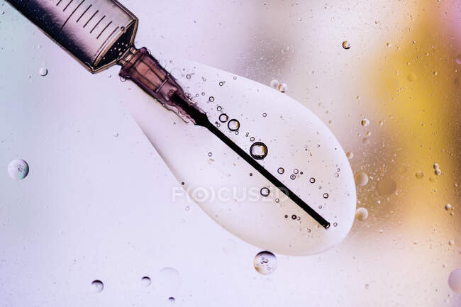Fechar a agulha da seringa cheia com a vacina do vírus injetado na célula sobre fundo turvo — Fotografia de Stock
