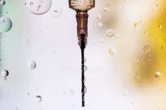 Closeup of needle of syringe filled with vaccine from virus injected in cell on blurred background — Stock Photo