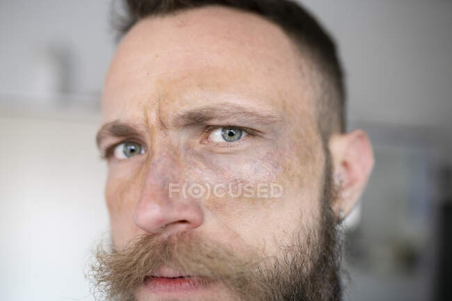 Хипстер с бородой смотрит в камеру и с лицом с киношным макияжем — стоковое фото