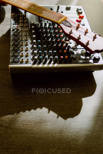 From above mixing console and crop guitar on table on sunlight — Stock Photo