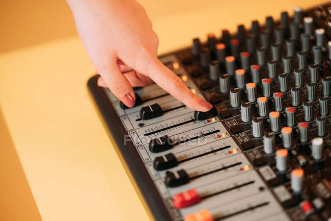 Рука женщины, использующей эквалайзер в музыкальной студии на размытом фоне — стоковое фото