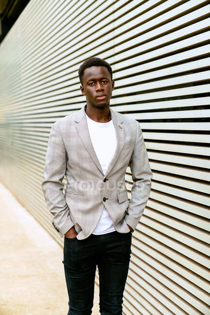 Side view of a fashionable young African American man looking away from a city wall — Stock Photo