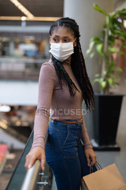 Portrait of attractive young afro latin woman wearing a facemask and holding shopping bags in commercial mall, Colombia — Stock Photo