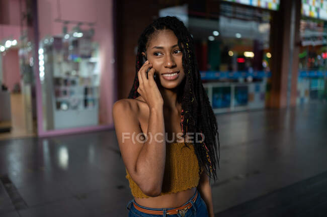Portrait d'une jeune femme afro latine heureuse parlant sur un smartphone dans un centre commercial, en Colombie — Photo de stock