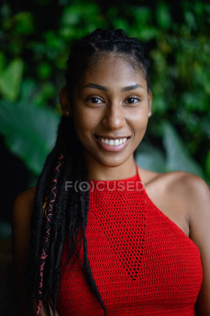 Retrato de mujer latina afro joven feliz con rastas en una parte superior roja del ganchillo, Colombia - foto de stock