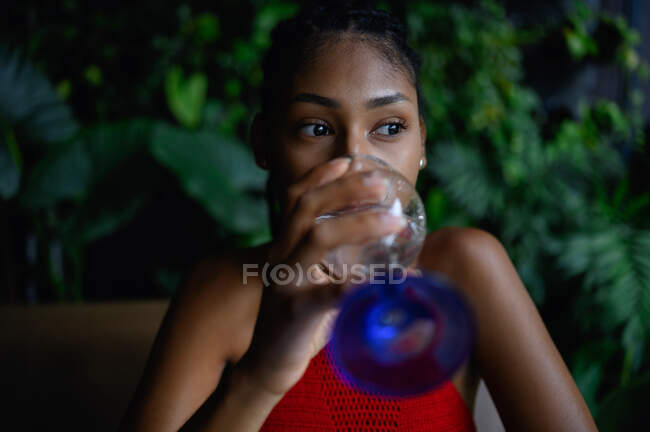 Приваблива молода африкано - латина жінка з дредами в крокеті з червоним топ - напоями вода в ресторані, Колумбія. — стокове фото
