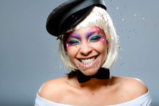 Menina loira com cabelo curto e maquiagem colorida se divertindo com confete — Fotografia de Stock