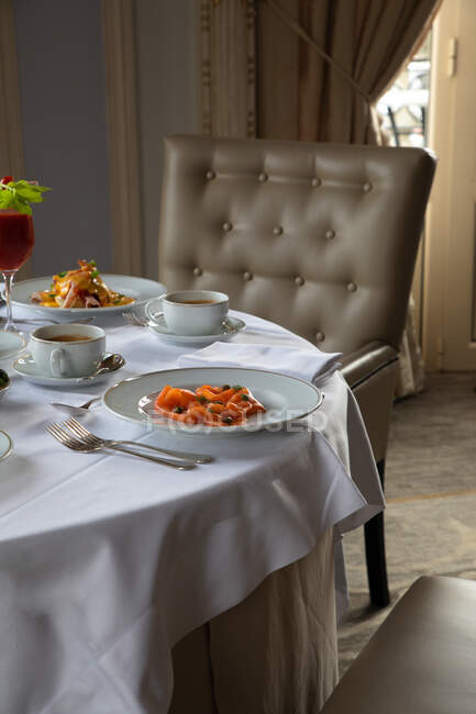 Verschiedene farbenfrohe Gerichte und Säfte am runden Tisch während des Frühstücks im eleganten Hotelrestaurant am sonnigen Morgen serviert — Stockfoto