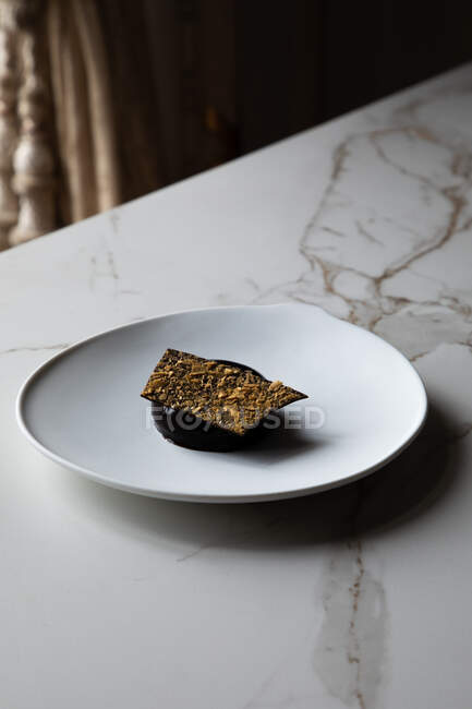 Сверху торт из шоколадного мусса с хрустящей карамелью на белой тарелке на мраморном столе — стоковое фото