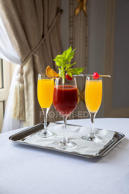 Crystal glasses of assorted refreshing squeezed juices decorated with leaves and fruit slices served on tray on table in restaurant — Stock Photo