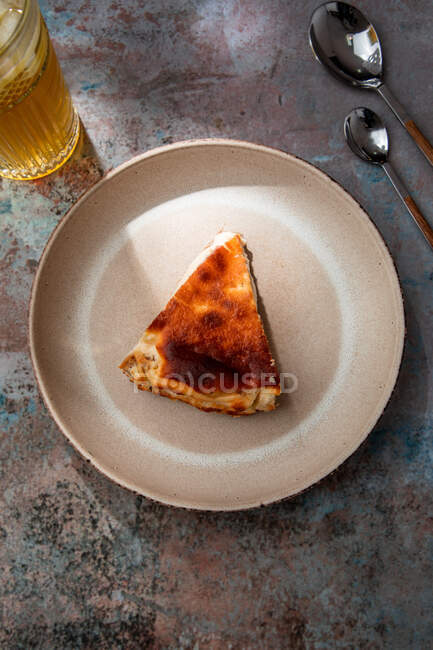 From above of appetizing pie placed on ceramic plate with glass of drink with ice in restaurant — Stock Photo