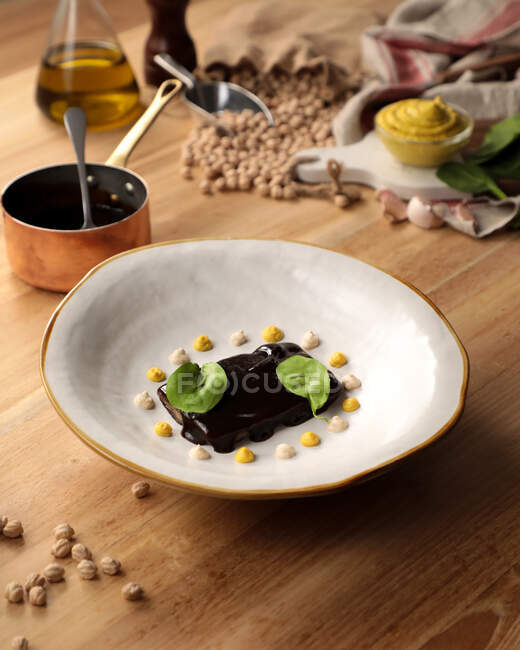 Dall'alto di dolce dessert di cioccolato decorato con foglie verdi e crema in ristorante gourmet — Foto stock