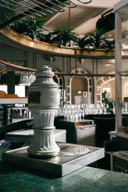 Інтер'єр стильного ресторану зі скляним посудом та пивним краном на овальній барній стійці під стелею, прикрашеною горщиками з рослинами — стокове фото