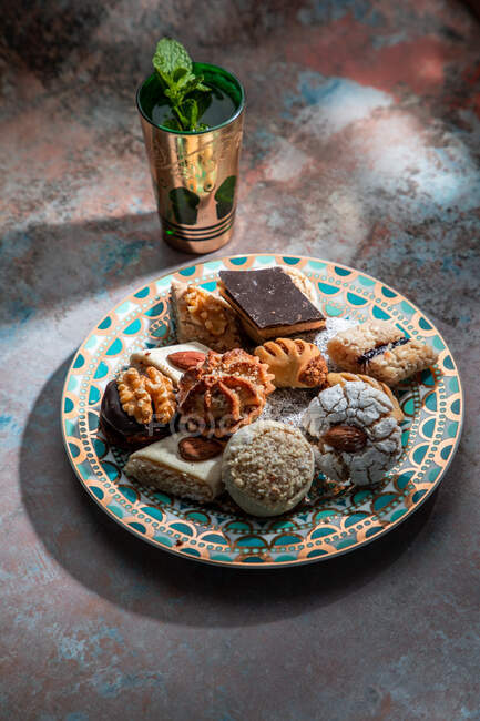 De cima de baklava e biscoitos com chá de hortelã-pimenta marroquina perto de faca e garfo colocados na mesa decorados com folhas de hortelã — Fotografia de Stock