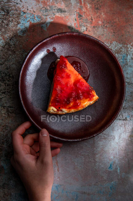 Top view of crop anonymous person with piece of delicious baked desert with berry jam — Stock Photo