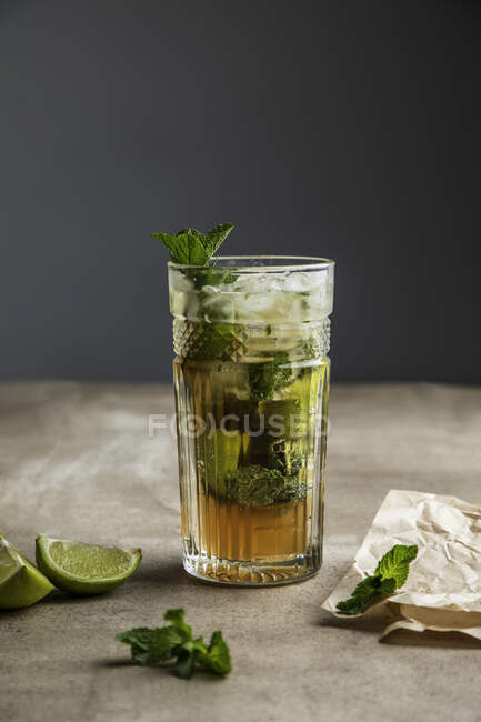 Erfrischender kalter alkoholischer Mojito mit Minzblättern und geschnittener Limette auf Holzbrett — Stockfoto