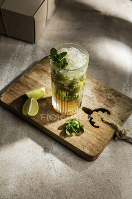 Dall'alto di rinfrescante mojito alcolico freddo con foglie di menta ghiaccio e calce tagliata su tavola di legno — Foto stock