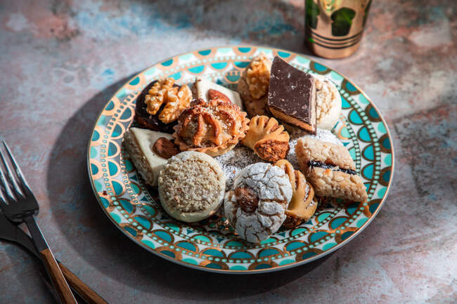 Dall'alto di baklava e biscotti con tè alla menta piperita marocchina vicino a coltello e forchetta posto sul tavolo decorato con foglie di menta — Foto stock