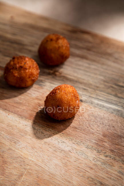 High angle of tasty roasted cheese balls on wooden cutting board in kitchen in ice steam — Stock Photo