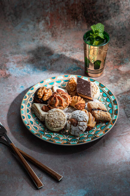 Von oben Baklava und Kekse mit marokkanischem Pfefferminztee in der Nähe von Messer und Gabel auf dem Tisch mit Minzblättern dekoriert — Stockfoto