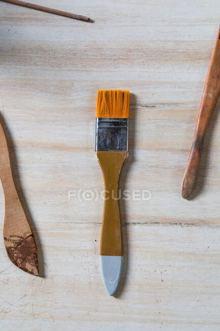 Conjunto de pinceles de cerámica y pintura colocados sobre mesa de madera en taller - foto de stock