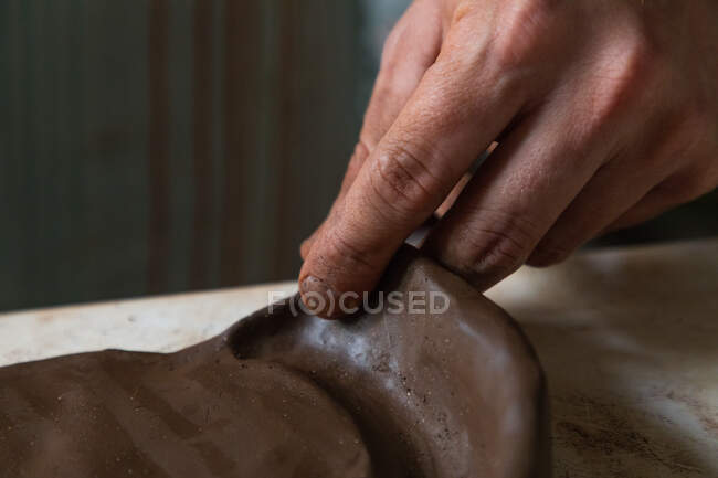 Dall'alto di raccolto anonimo pezzo di argilla maschile rotolamento artigianale durante la creazione di piatto in officina — Foto stock