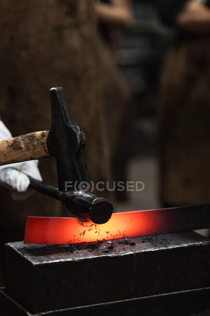 Unbekannter Handwerker hämmert bei Schmiedeprozess in Werkstatt heißes Eisenteil auf Amboss — Stockfoto