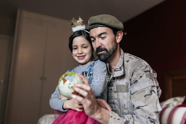 From below of positive soldier talking to daughter and pointing at place at globe before going to serve in army — Stock Photo